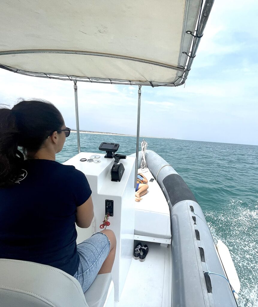 a woman driving a speedboat in the Ria formosa with her child